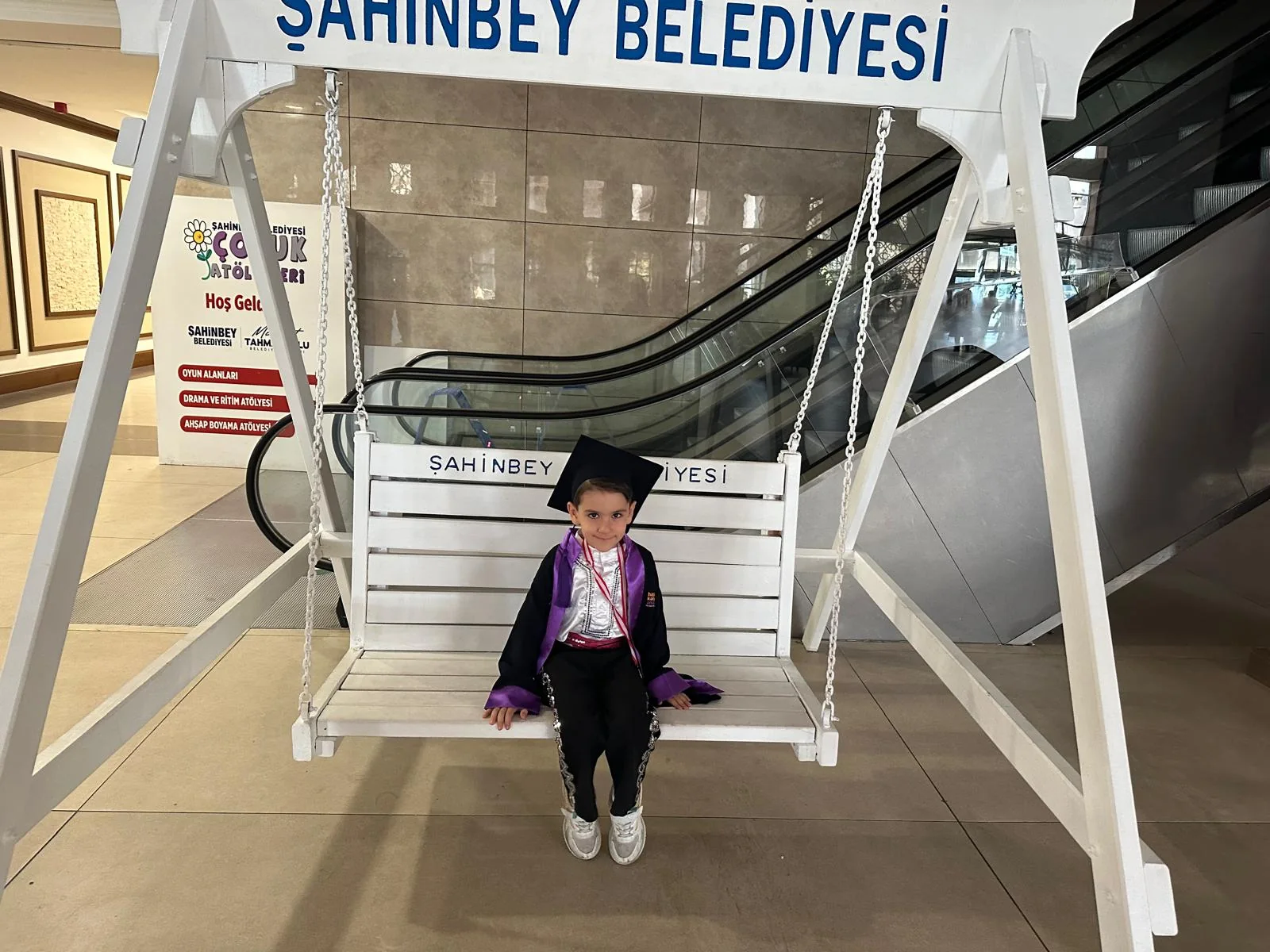 Mezuniyet kıyafetiyle beyaz salıncakta oturan Demir